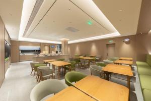 a restaurant with wooden tables and green chairs at Ji Hotel Beijing Daxing Airport Safari Park in Beijing
