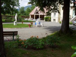 een park met een bank en een standbeeld en een gebouw bij Castel de la Pique in Luchon