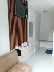 a living room with a couch and a tv on a wall at Mumzai House 2 in Ko Muk