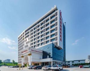 ein großes Gebäude mit auf einem Parkplatz abgestellten Autos in der Unterkunft Vienna International Shenzhen Tianan Digital City in Longgang