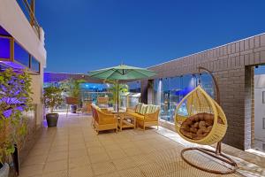 een terras met een tafel, stoelen en een parasol bij Hays AIR By Ahuja Residences - Golf Course Ext Road & Sector 51 in Gurgaon