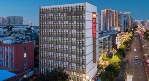 un grand bâtiment avec une enseigne dessus dans une ville dans l'établissement ibis Kunming Beijing Rd, à Kunming