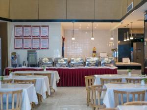 a dining room with tables and chairs with white table cloth at Zmax Hotel·Yantai Shimao Binhai Plaza in Yantai