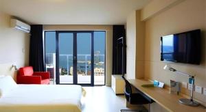 a hotel room with a bed and a large window at Jinjiang Inn Sanya Jiefang Road Tax Free Shopping Center in Sanya