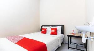 a bedroom with a bed with red pillows and a sink at Hotel O Wisma Pelita Mas in Pampang