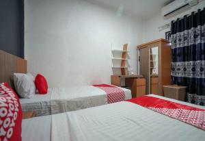 Zimmer mit 2 Betten mit roter und weißer Bettwäsche in der Unterkunft Hotel O Green Palm Kostel Syariah in Tabahpingin
