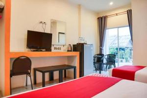 ein Hotelzimmer mit einem Bett und einem Schreibtisch mit einem Fernseher in der Unterkunft OYO 902 Life and Love Resort in Ban Khlong Haeng