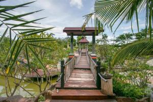 eine Holzbrücke über einen Wasserkörper in der Unterkunft OYO 1140 Piyapruk Resort at Khaoyai in Ban Khanong Phra Klang (1)