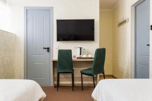 Zimmer mit einem Schreibtisch mit 2 Stühlen und einem TV in der Unterkunft Solief Hotel in Taschkent