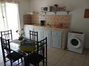a kitchen with a table and a washing machine at Residence Virginie in Saint-Leu