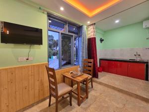 eine Küche mit einem Tisch und einem TV in einem Zimmer in der Unterkunft Aangan Royal Stay- Your Mountain Home in Dharamshala in Dharamsala