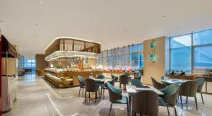 un restaurant avec des tables et des chaises et un bar dans l'établissement New Century Hotel Nanjing, à Pukou