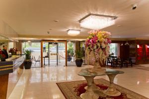 um lobby com um vaso de flores sobre uma mesa em Amman International Hotel em Amã