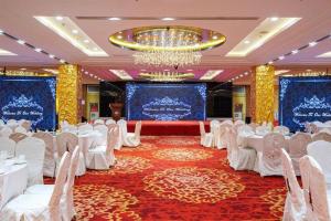 a banquet hall with white tables and chairs and a chandelier at Inzone Garlnd Hotel Zhangqiu in Zhangqiu