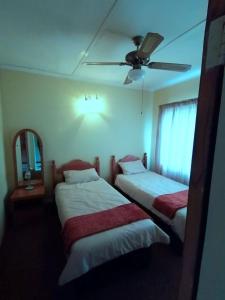 2 camas en una habitación de hotel con ventilador de techo en Green Trees Cottage, en Nelspruit