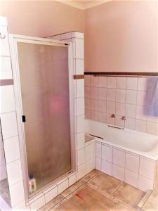 una ducha con puerta de cristal en un baño en Green Trees Cottage, en Nelspruit