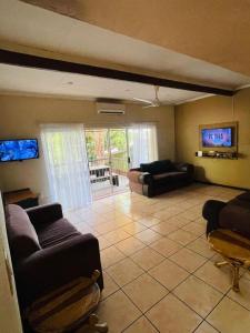 Una gran sala de estar con sofás y un televisor. en Green Trees Cottage, en Nelspruit