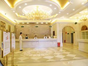 Ein Mann steht in einer Hotellobby mit einer Theke. in der Unterkunft Vienna Hotel Shenzhen International Exhibition Center Fuhai Qiaotou in Fenghuangwei