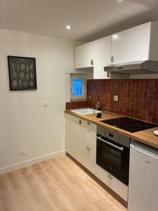 a kitchen with white cabinets and a black stove top oven at Appartement Chic 4 personnes - Plein Centre Historique in Angers +3 photos
