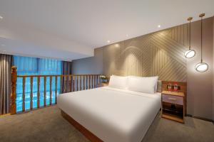 ein Schlafzimmer mit einem großen weißen Bett und einem Balkon in der Unterkunft Orange Hotel, Beijing Daxing Biomedicine Base in Peking