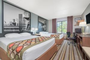 a hotel room with two beds and a desk at Super 8 by Wyndham Bloomington/Airport in Bloomington +33 photos