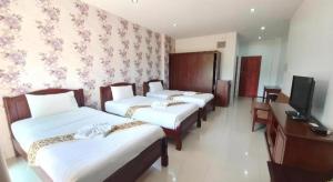 a hotel room with three beds and a television at Doungta Anda Hotel Krabi in Ban Khlong Chi Lat