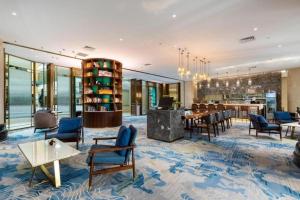 un hall d'entrée avec des chaises et des tables et un bar dans l'établissement Bliss International Hotel Weihai, à Weihai