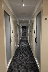 Un pasillo con un largo corredor con puertas y suelo ajedrezado. en NapzBox, en Petaling Jaya