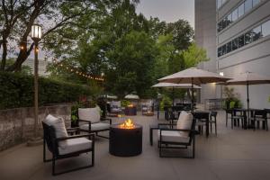 eine Terrasse mit Tischen, Stühlen und einer Feuerstelle in der Unterkunft Embassy Suites by Hilton Detroit Troy Auburn Hills in Troy