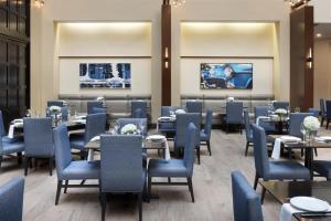 ein Esszimmer mit Tischen und blauen Stühlen in der Unterkunft Embassy Suites by Hilton Detroit Troy Auburn Hills in Troy