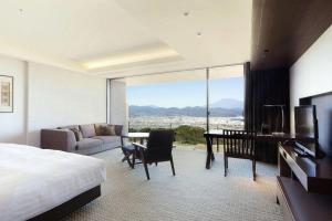 a bedroom with a bed and a living room with a view at Nippondaira Hotel in Shizuoka