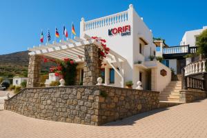 a white building with a stone wall and some flags at Korifi Suites - JR Villas Adults Only in Hersonissos