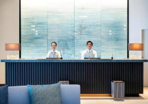 Zwei Männer sitzen an einer Theke in einem Zimmer in der Unterkunft Goto Tsubaki Hotel in Hukue