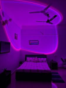 a purple bedroom with a bed and a ceiling fan at Puhor Inn in Sivasagar