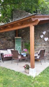a patio with three chairs and a table and a stone wall at Casa De Aldea La Galea in Vegadeo