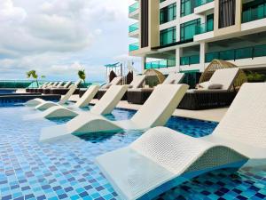 a row of white lounge chairs in a swimming pool at Seafest Hotel Semporna in Semporna