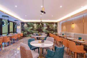 ein Restaurant mit Tischen und Stühlen und eine Wand mit Pflanzen in der Unterkunft Orange Hotel, Beijing Daxing Biomedicine Base in Peking