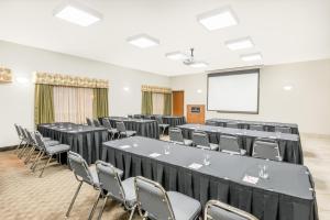 a conference room with tables and chairs and a screen at Ramada by Wyndham Olds in Olds