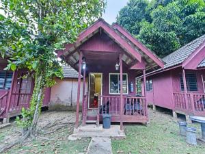a pink house with a porch and a door at OYO 90620 Mahseer Chalet in Kuala Tahan