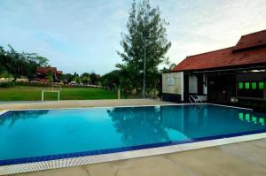 une grande piscine bleue à côté d'une maison dans l'établissement OYO Home 90745 Desa Balqis Beach Resort, à Kampong Tanjong Dahan