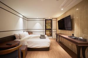a bedroom with a bed and a desk and a television at 컬리넌 호텔 앤 스파 in Seoul
