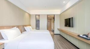 a bedroom with a large white bed and a flat screen tv at Borrman Hotel Xiamen Xiang'an Maxiang in Xiang'an