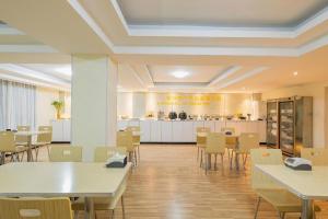 a dining room with tables and chairs and a kitchen at JTOUR Inn Xiantao Shopping Mall Pedestrian Street in Xiantao