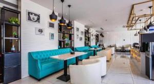 ein Restaurant mit einem blauen Sofa sowie Tischen und Stühlen in der Unterkunft Xana Lite·Chengde Xinglong County in Xinglong