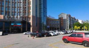 ein Parkplatz mit Autos vor den Gebäuden in der Unterkunft James Joyce Coffetel· Yinchuan International Exhibition Center Wanda Square Qinshui Street in Yinchuan