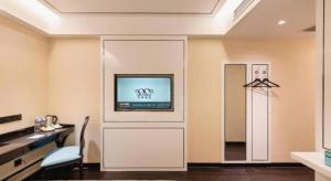 a living room with a tv on a wall at Xana Hotelle· Dalian Software Park University of Technology in Dalian