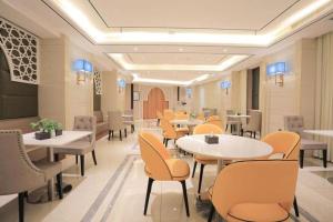 ein Restaurant mit Tischen und Stühlen in einem Raum in der Unterkunft Jinjiang Inn Select Urumqi Midong Avenue in Miquan
