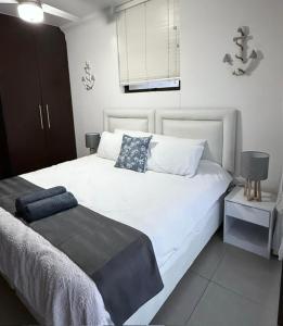 une chambre avec un grand lit blanc avec des oreillers bleus dans l'établissement Coral Reef 502, à La Mercy 19 autres photos