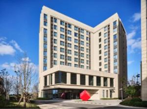 ein großes weißes Gebäude mit einem roten Objekt davor in der Unterkunft Q Hotel Shanghai Pudong in Shanghai