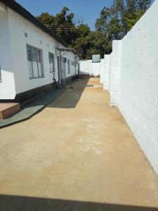 eine weiße Backsteinmauer neben einem Gebäude in der Unterkunft Lajoy Executive Lodge in Lusaka